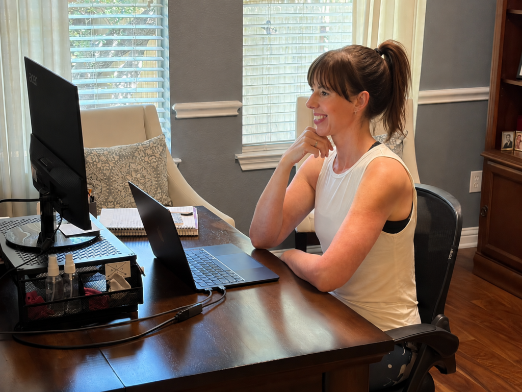 This image shows a personal trainer meeting online with a training client. She has been hired to create a wellness program for the company's employees.
